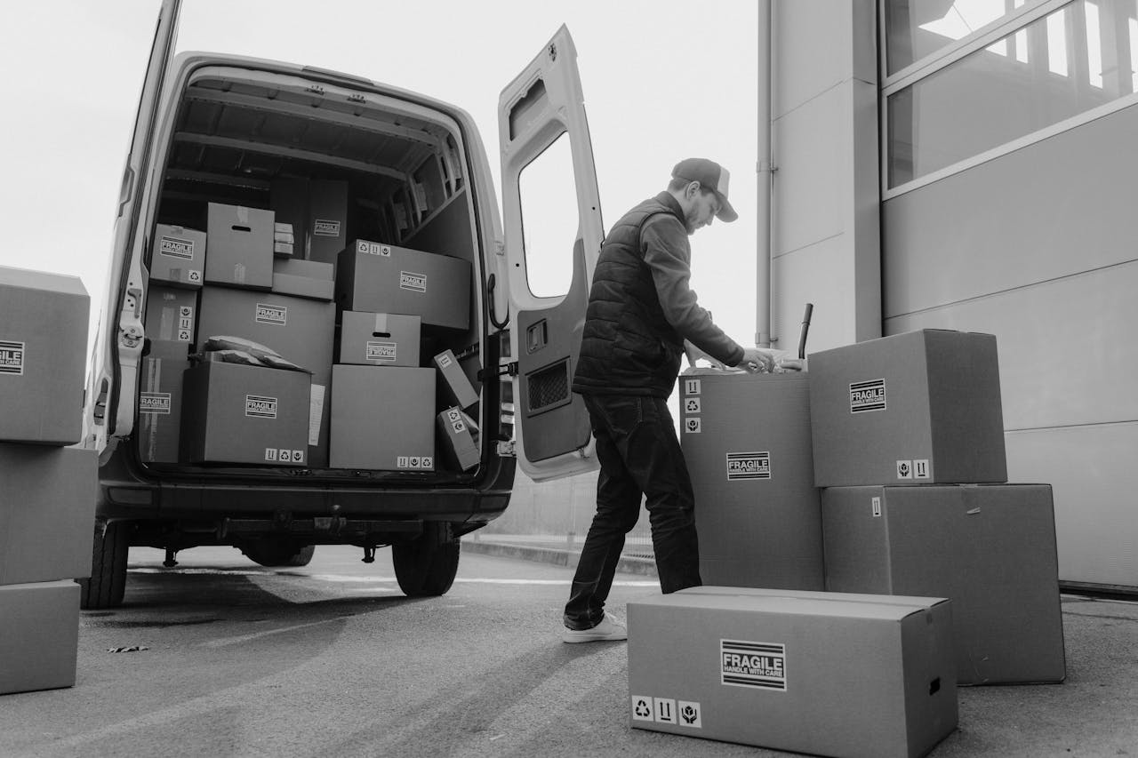 services-02 Delivery driver unloads packages from a van, organizing shipments outdoors.