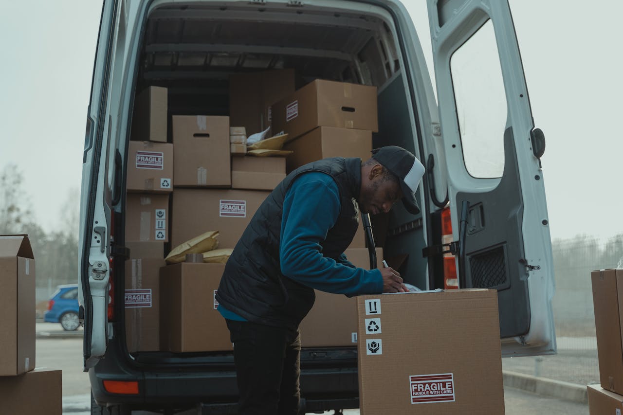 gallery-4 Delivery man sorting packages in van, organizing shipments for distribution.