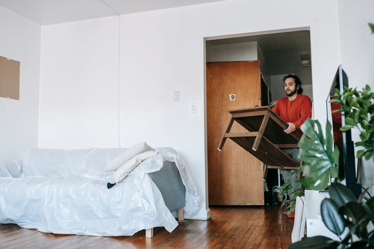 gallery-6 Man holding a wooden table during relocation in a contemporary apartment.